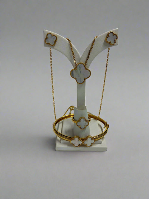 Gold necklace and bracelet set on a white display stand with a white background