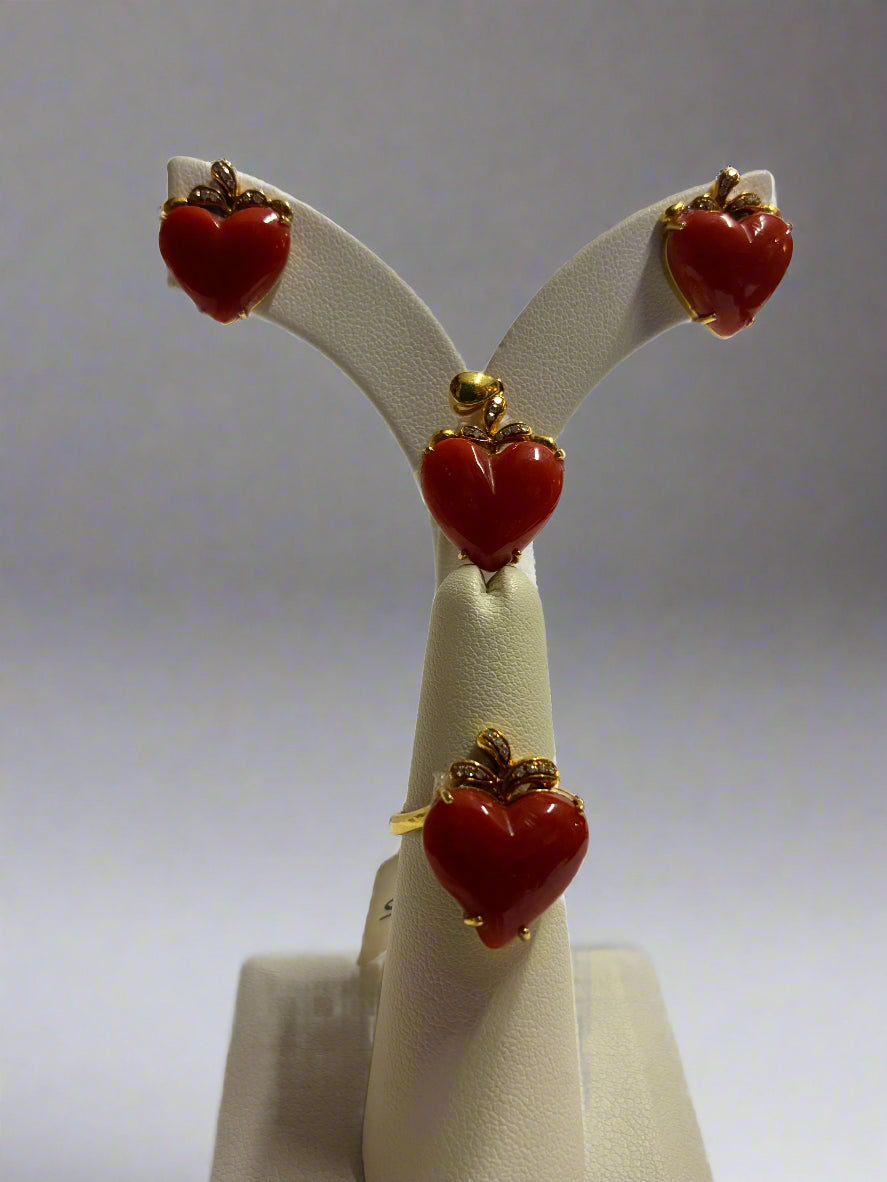 Heart-shaped earrings and ring on a white stand with a white background